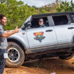 A participant in Ford's Bronco Off-Roadeo is coached through a maneuver